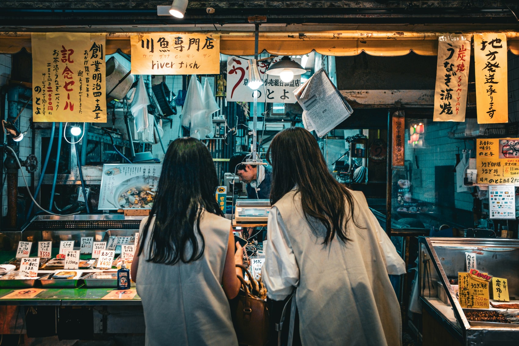 two girls look over the sushi options at a stall